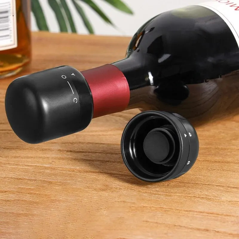 A black and red silicone wine bottle stopper is shown resting on a wooden surface.
