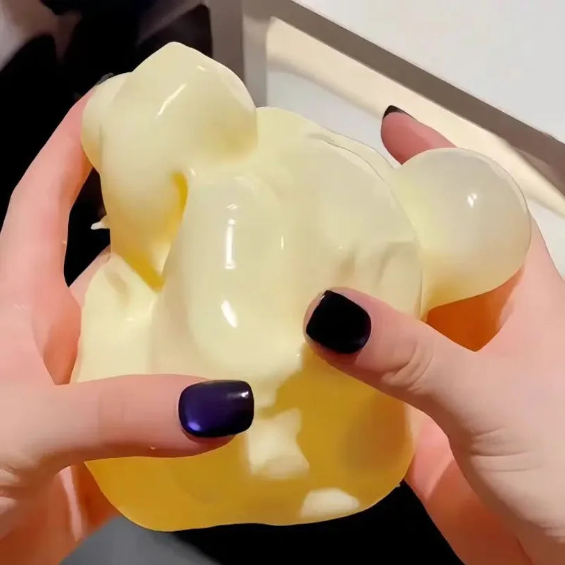 A hand holds a yellow, squishy stress relief toy shaped like a cheese, filled with Vaseline.