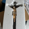 A resin sculpture of the Easter Cross crucifix with a figure of Jesus Christ on a wooden cross, displayed in white foam packa