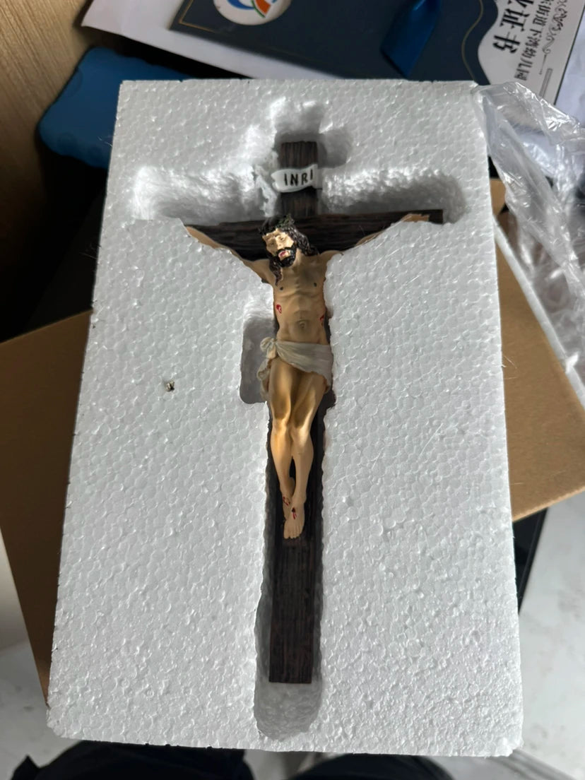 A resin sculpture of the Easter Cross crucifix with a figure of Jesus Christ on a wooden cross, displayed in white foam packa