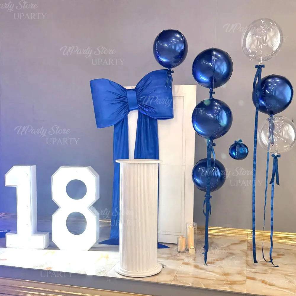 A display featuring blue foil balloons tied with ribbon and large white number balloons for an 18th birthday celebration.