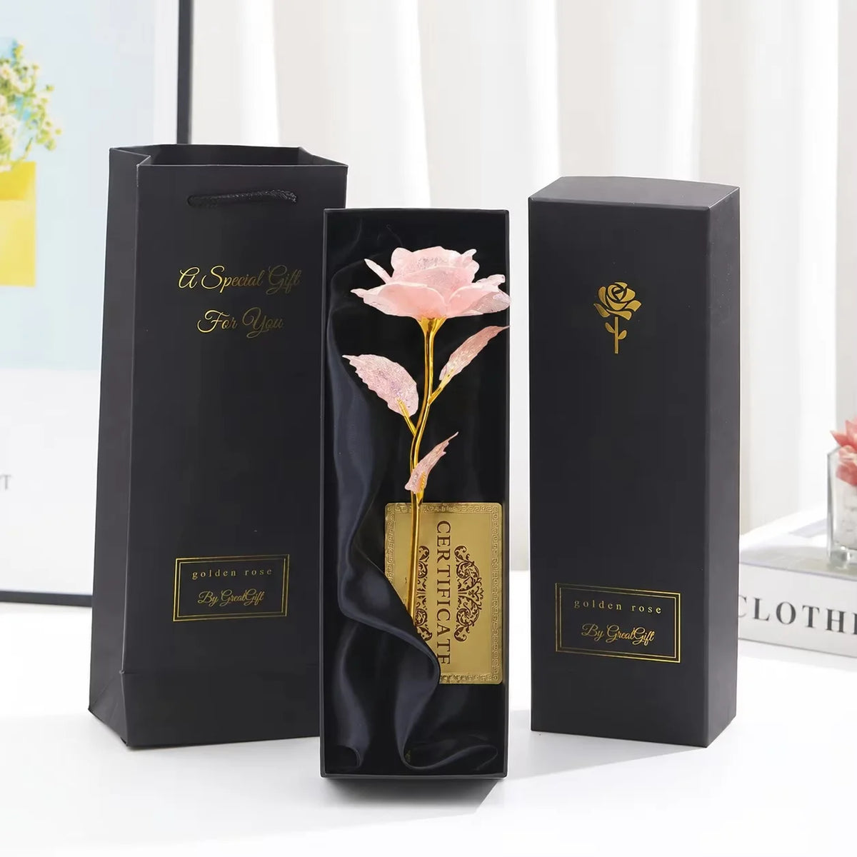 Three black gift boxes with gold foil accents and a pink rose design displayed on a white surface.