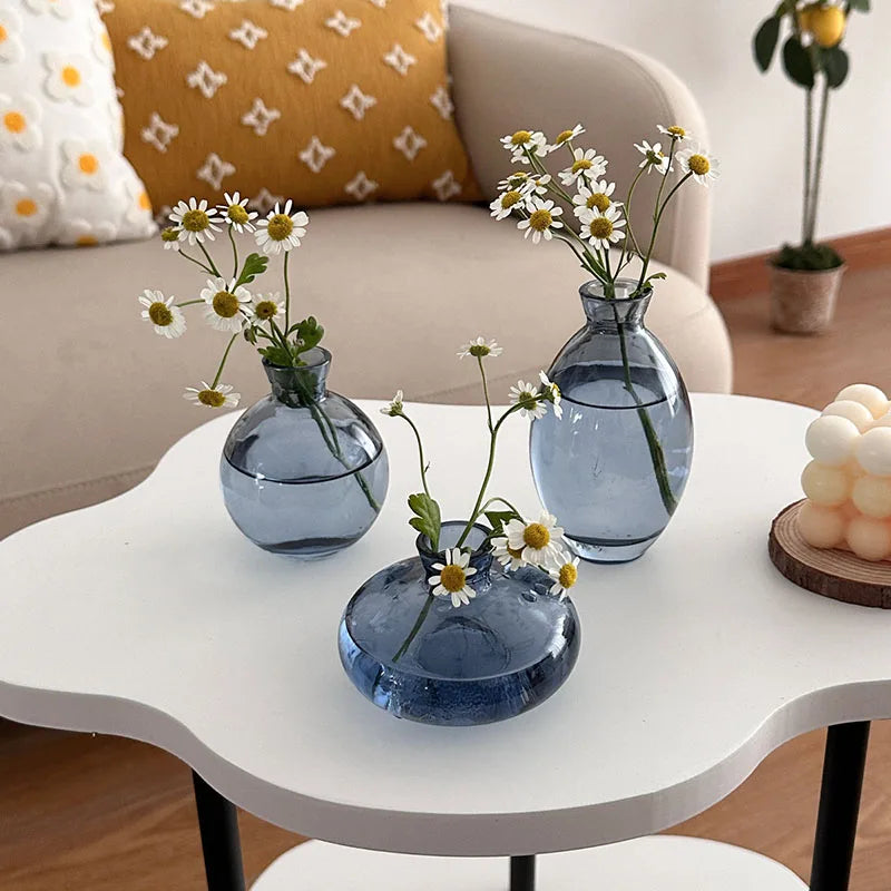 A set of three minimalist blue glass bud vases displayed on a white table.
