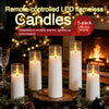 A set of five white LED flameless candles in glass holders displayed on a dark surface with festive greenery.