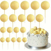 A collection of gold and silver foam ball cake toppers on sticks for party decorations