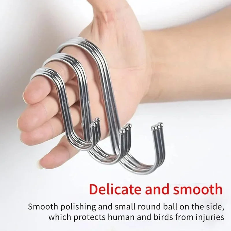 A hand holds a set of ten S-shape stainless steel hanging hooks demonstrating their smooth polishing and protective features.