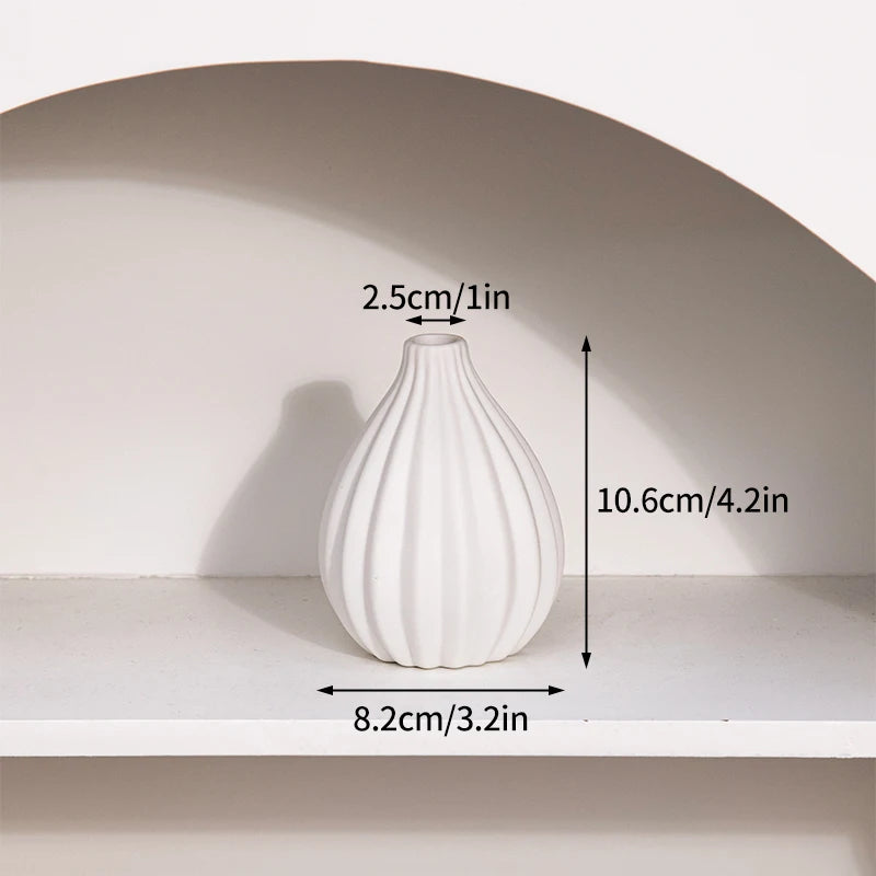 A white ceramic bud vase with a curved shape is displayed on a shelf, showing its dimensions.