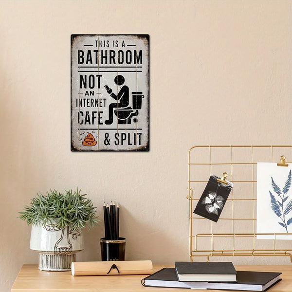 A vintage metal tin sign reads This is a bathroom not an internet cafe & split on a light beige wall.
