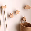 Decorative wooden animal hooks, including a cat, rabbit, and tree, mounted on a white wall.
