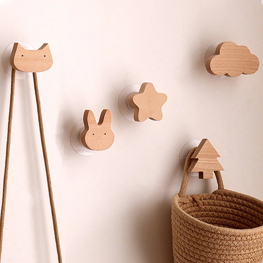 Decorative wooden animal hooks, including a cat, rabbit, and tree, mounted on a white wall.
