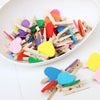 A collection of colorful mini wooden photo clips in various shapes and colors scattered on a white surface.