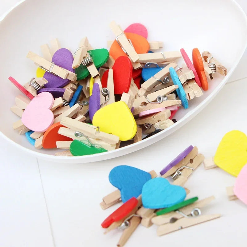 A collection of colorful mini wooden photo clips in various shapes and colors scattered on a white surface.