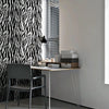 A modern interior featuring a black and white zebra print wall, a desk with a chair, and vertical blinds.