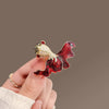 A vintage marine life brooch pin featuring a gold-colored fish with red and silver glitter details.