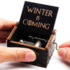 A carved wooden music box with an open lid displaying the text Winter is coming