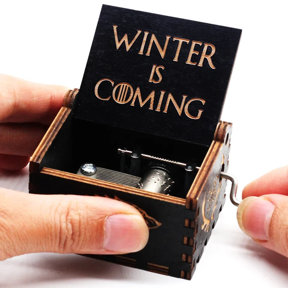 A carved wooden music box with an open lid displaying the text Winter is coming