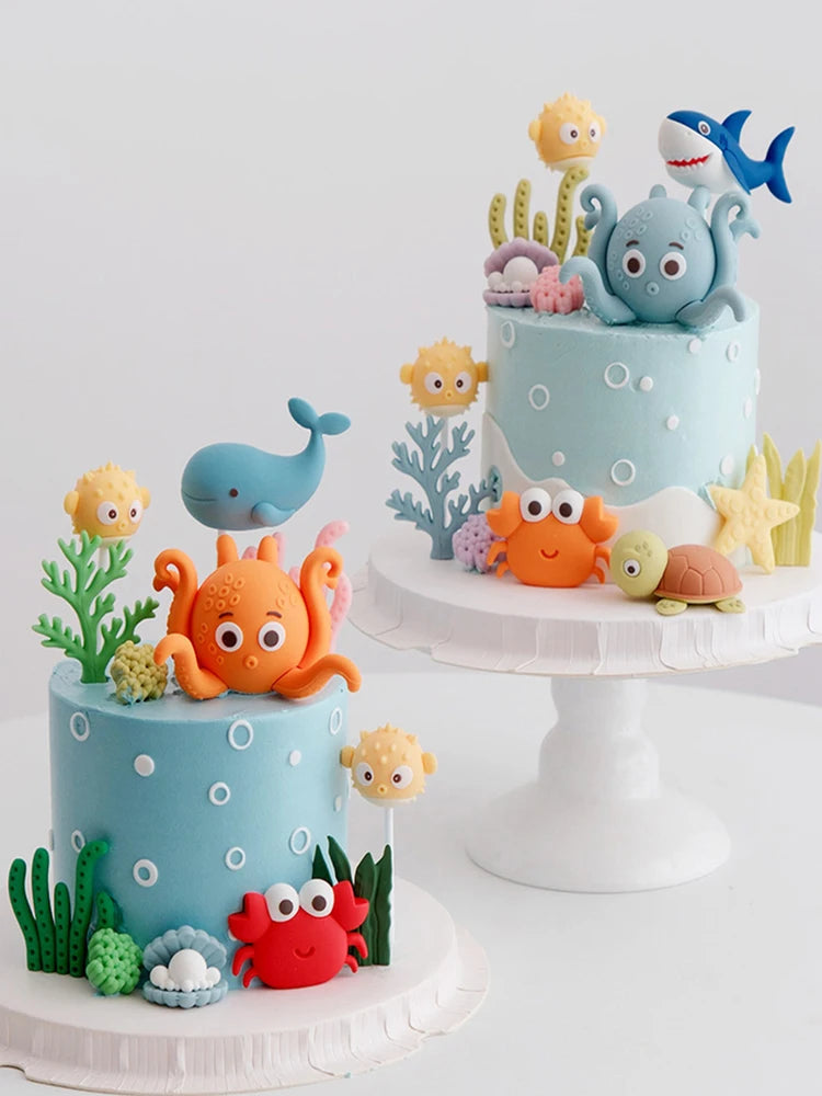 A tiered cake decorated with ocean animal toppers including a whale, octopus, and turtle.