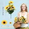 A young woman holds a bouquet of artificial yellow sunflowers in a woven basket.