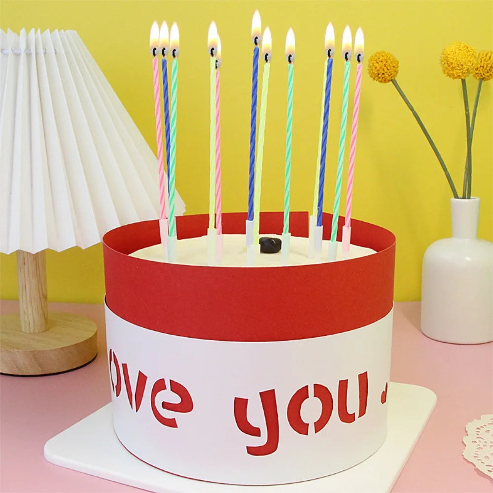 A red and white cake candle holder with 'love you' text on the side, surrounded by thin spiral birthday candles.