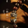 A close-up of a dark brown wooden bracelet featuring semi-jade beads and an ornate metal charm.