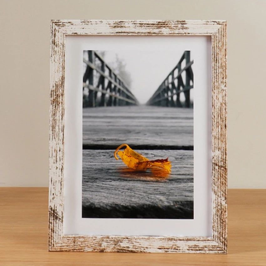 A framed black and white photograph of a yellow fish lying on a wooden surface.