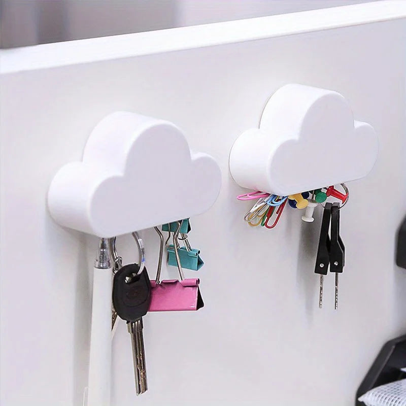 A white magnetic cloud key hanger displaying various keys and small items on a white wall.