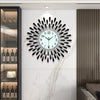 A modern minimalist metal wall clock with a black face and silver accents mounted on a white marble wall.