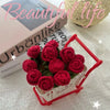 A bouquet of hand-crocheted red roses displayed in a white basket on a light surface.