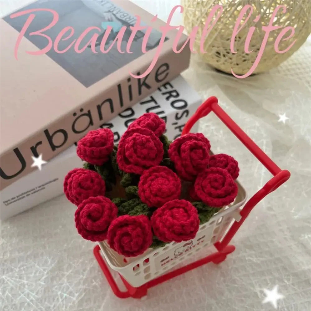 A bouquet of hand-crocheted red roses displayed in a white basket on a light surface.