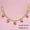 Gold chain necklace with red cherry charms and green leaves, measuring 26.5cm long.