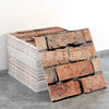 A stack of rectangular marble peel-and-stick tiles with gold accents displayed on a gray surface.