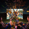A family is watching a movie projected onto an Anti-Light HD Projection Screen outdoors at night.