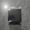 A black square storage holder for a scale with a self-adhesive mount, packaged in clear plastic.