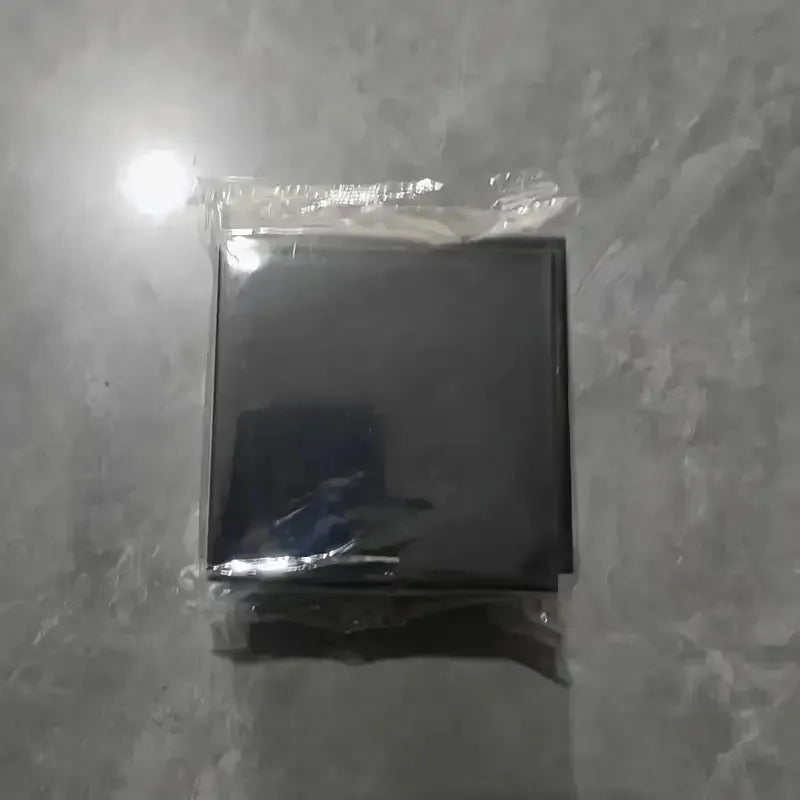 A black square storage holder for a scale with a self-adhesive mount, packaged in clear plastic.