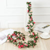 A silk rose garland featuring pink and red roses draped vertically on a white pillar against a white wall.