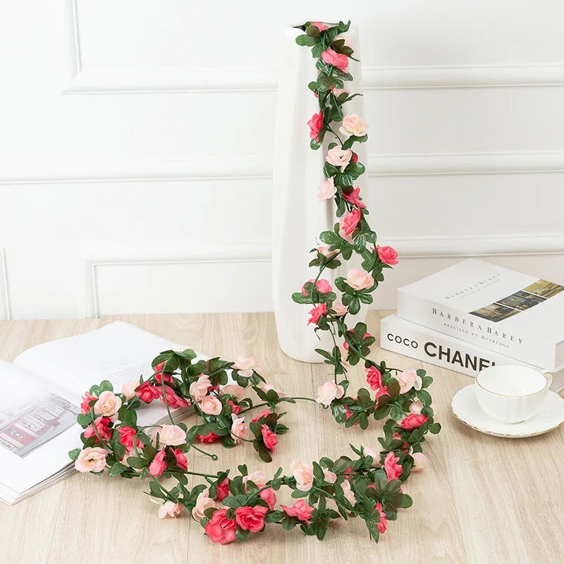 A silk rose garland featuring pink and red roses draped vertically on a white pillar against a white wall.