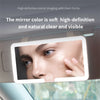 A vanity mirror mounted in a car sun visor showing a woman's face with soft, high-definition lighting.