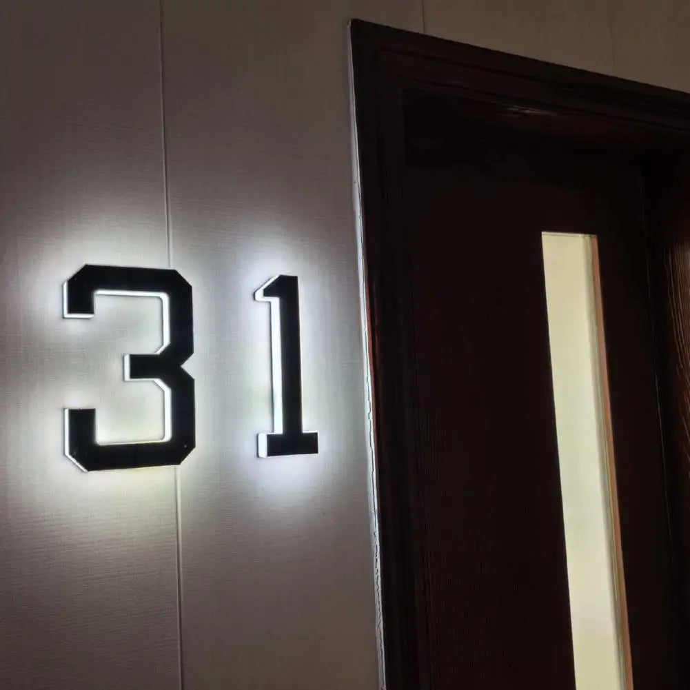 A close-up of a modern house number sign displaying the number 31 mounted on a light-colored wall.