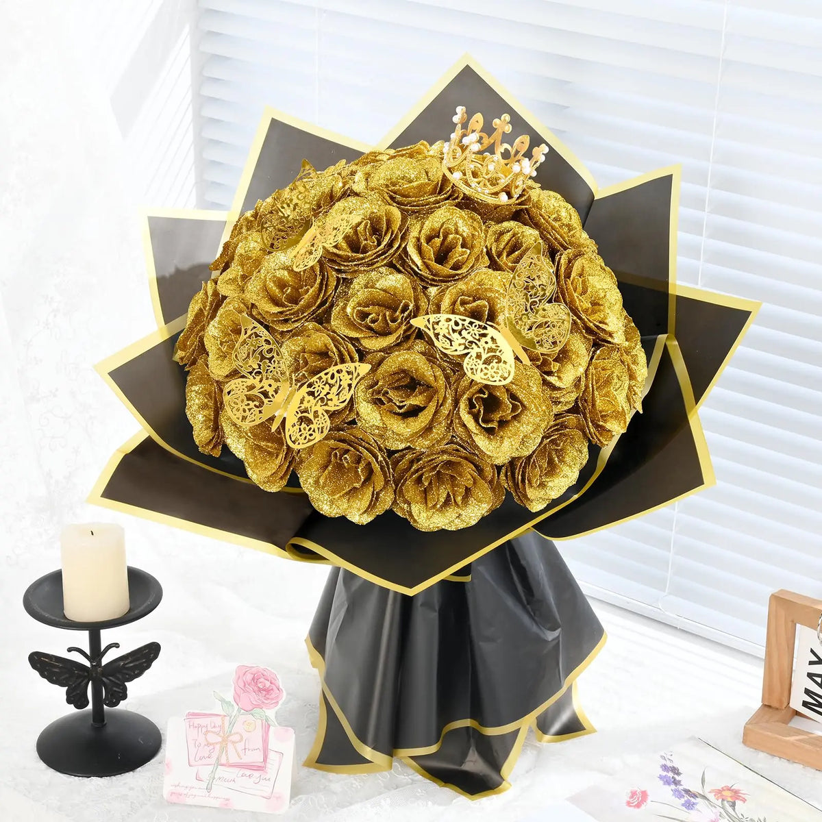 A bouquet of twelve artificial gold roses displayed on a black and gold stand.