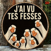 A round wooden sign featuring a humorous illustration of several white ducks with orange beaks against a black background.