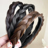 A hand holds several black and brown braided hair bands for fashion and party