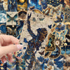 A hand holds a small packet of retro space and planet stickers against a richly patterned background.