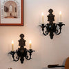 Vintage black wall-mounted double candle holder with multiple arms and candlesticks.