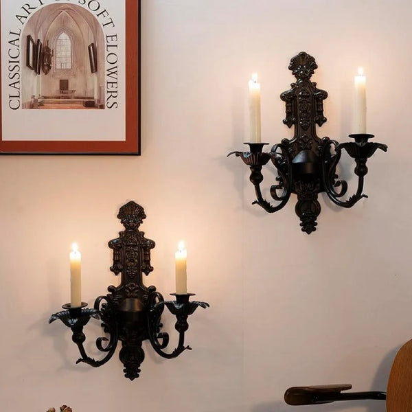 Vintage black wall-mounted double candle holder with multiple arms and candlesticks.