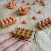 A hand holds a small, light brown, hexagonal miniature food item used for dollhouse or collector sets.
