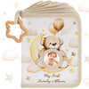 A beige fabric photo album cover featuring a teddy bear and a baby's face on a crescent moon against a cloud background.