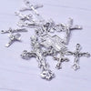 A collection of antique silver cross charms and pendants for jewelry making displayed on a white surface.