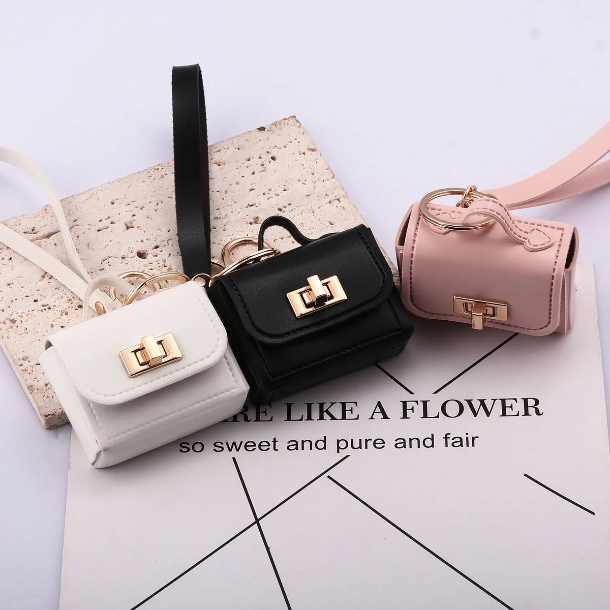 A set of mini leather openable bags in black and pink with gold hardware displayed on a white background.