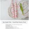 Two light pink long-stemmed candles with small red hearts print displayed on a silver tray