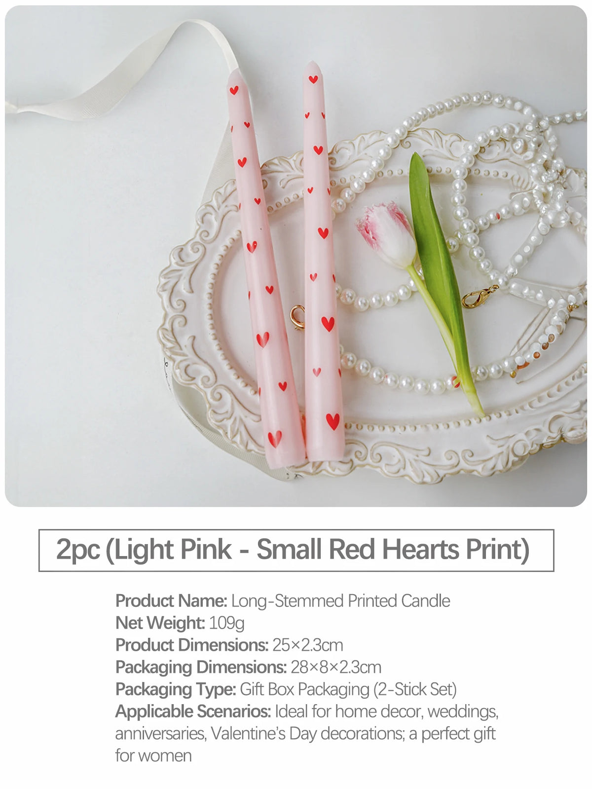 Two light pink long-stemmed candles with small red hearts print displayed on a silver tray